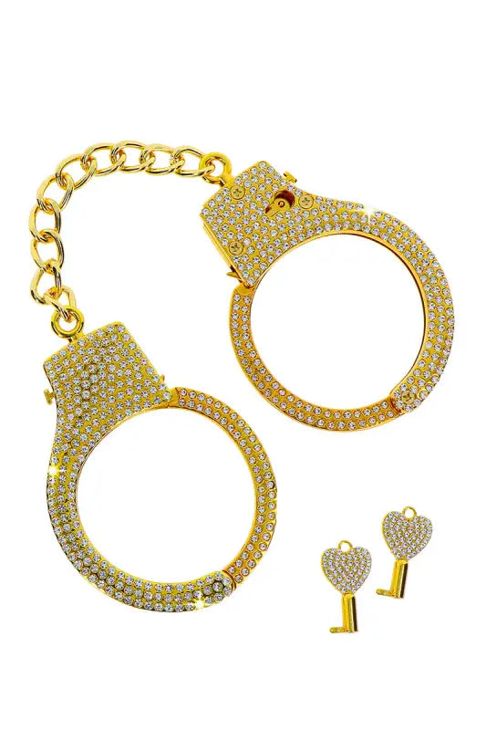 Menottes dorées, recouvertes de strass, avec des clés en forme de cœur.