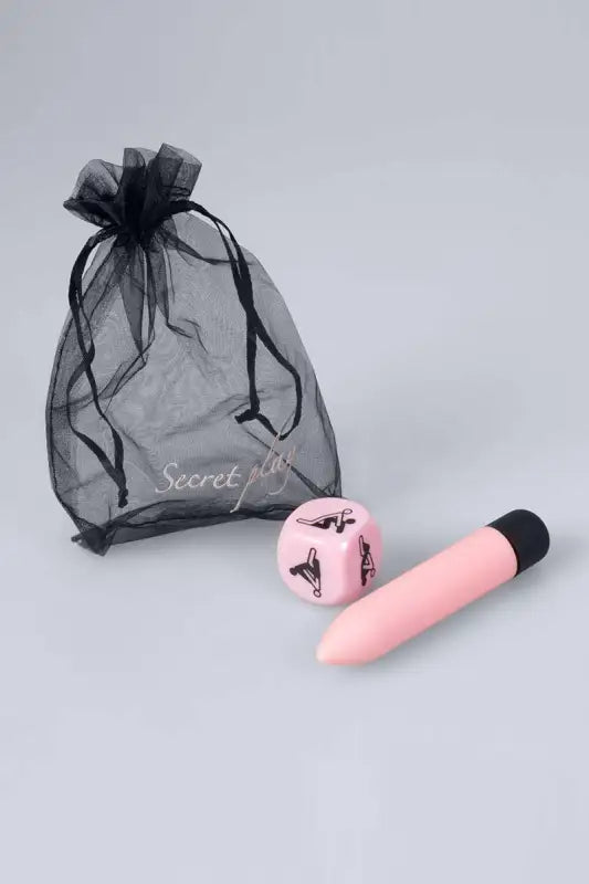 Vibrateur rose avec embout noir et dé sexuel.