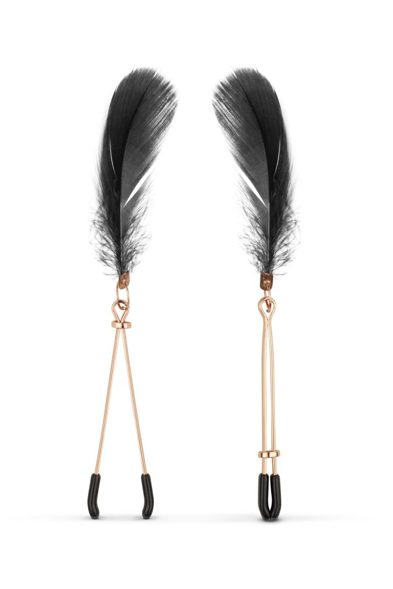 Les pinces tétons couleur rose gold avec embouts en plastique noir, et des plumes noires, comprises dans le kit BDSM 